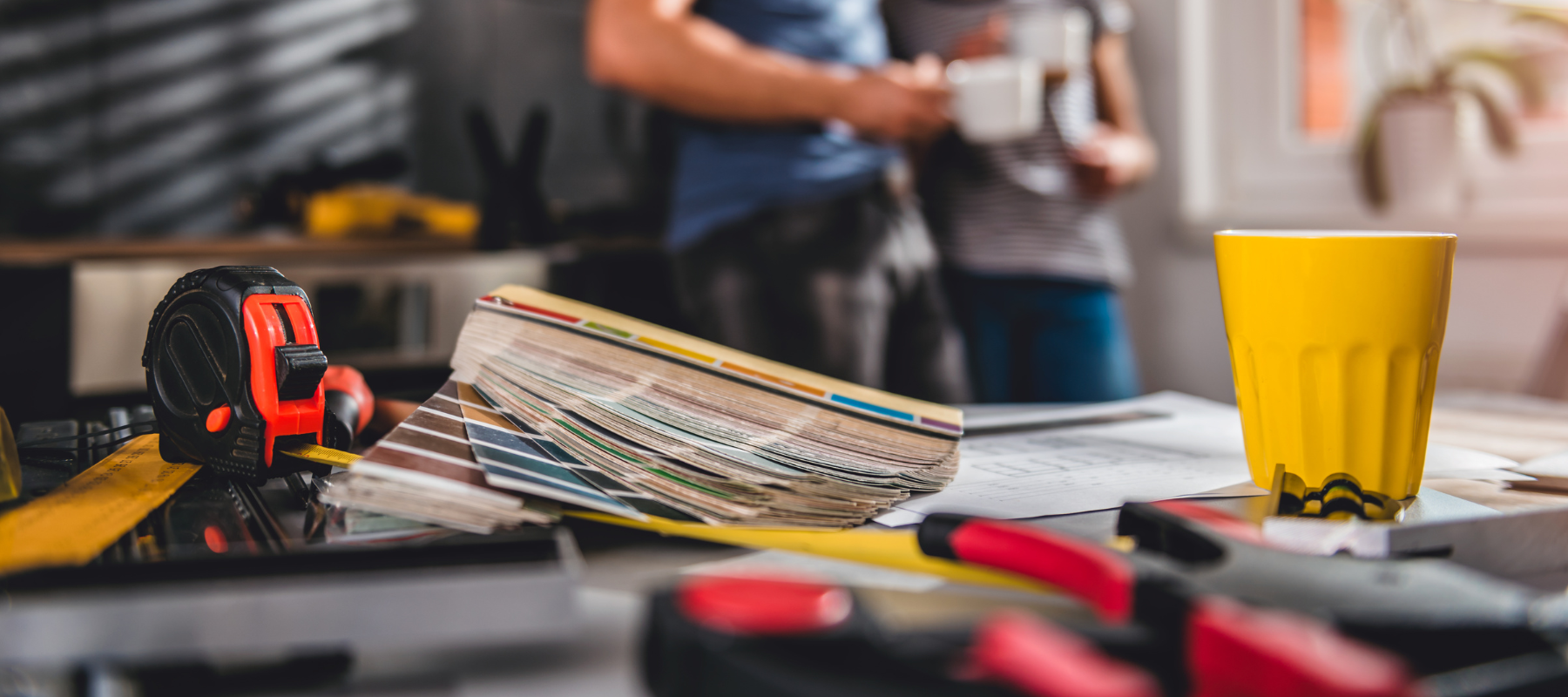 Power tools and supplies laid across a counter with a couple standing in the background.